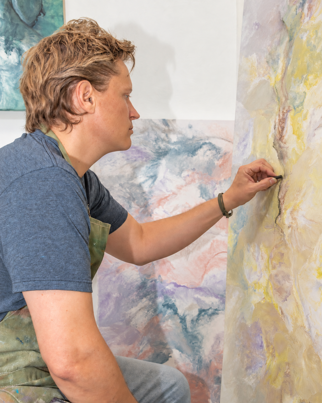 A close view of Daniel Baker drawing with charcoal on a pale yellow painting.