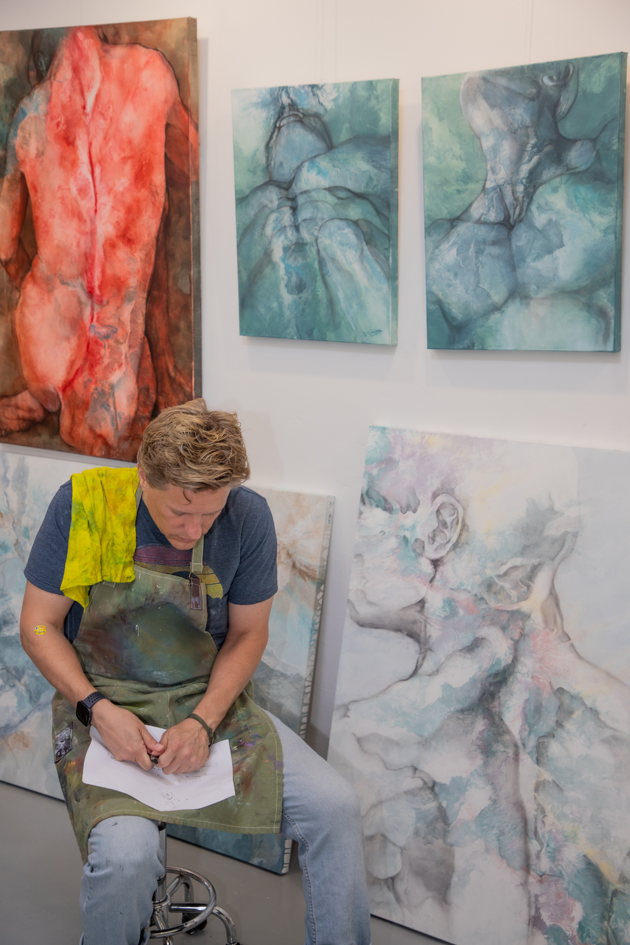 Daniel Baker seated in his studio, surrounded by his paintings.
